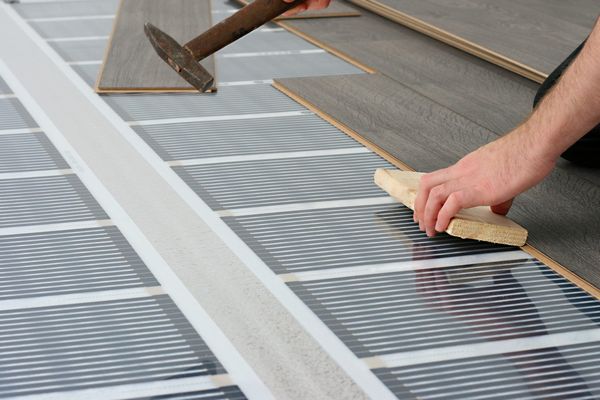 Man installing laminate floor over infrared carbon heating system